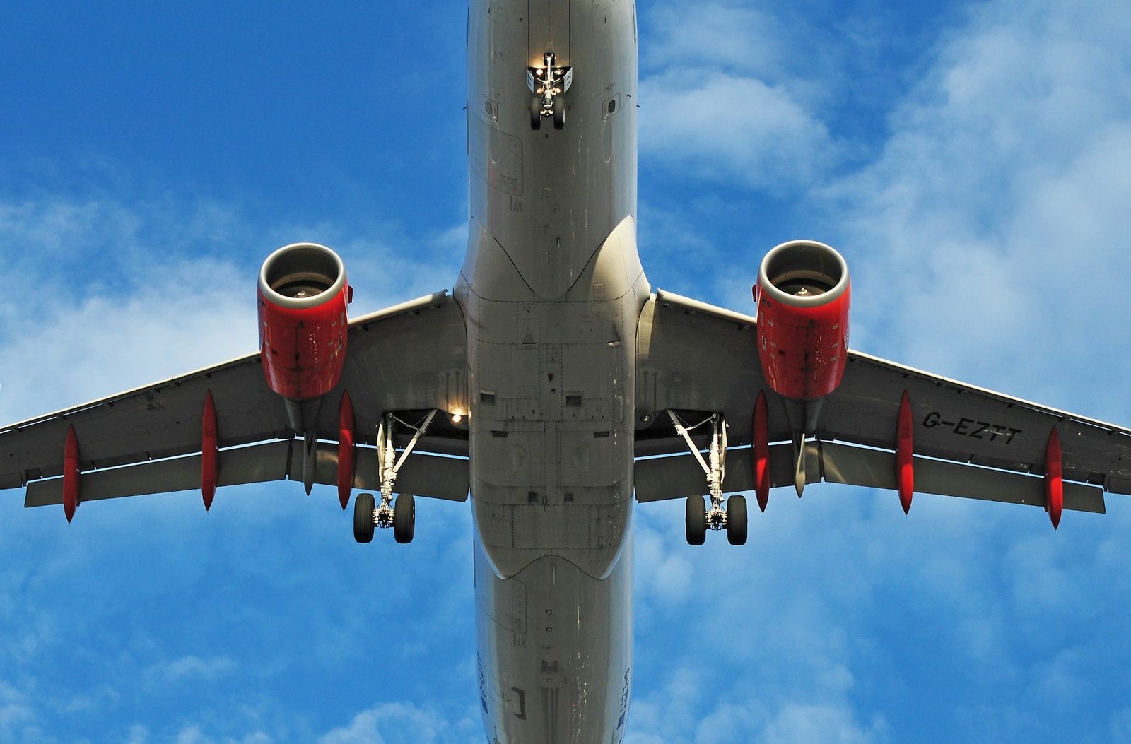 Aeronave em aproximação vista por baixo, com trem de pouso e superfícies aerodinâmicas estendidos.